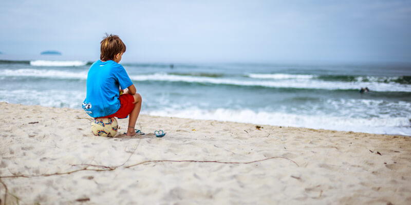 Child Sitting on a ball on the beach