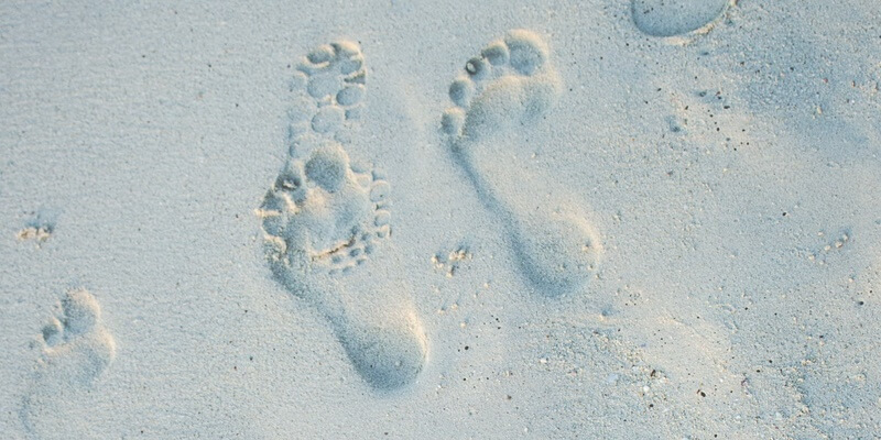 Footprints in sand signifying separated parents and holidays with children