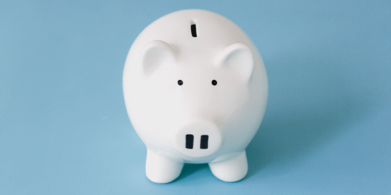 White piggy bank on blue background signifying divorce and finances