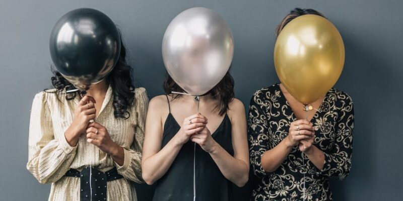 Party girls holding balloons signifying office Christmas parties