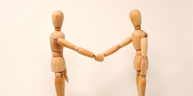 Wooden figures shaking hands in agreement symbolising terms and conditions