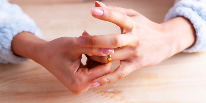 Woman taking wedding ring off symbolising divorce