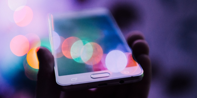 A smartphone held in hand with lights symbolising digital assets.