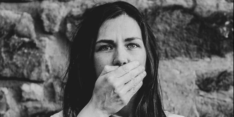 Woman with a hand over her mouth signifying defamation.