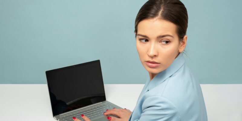 Female employee in pale blue suit looks warily over her left shoulder signifying Employment Rights Act Changes to Sexual Harassment and Whistleblowing legislation.