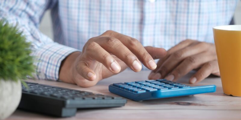 Close up of hands using a calculator in an office setting signifying statutory payment rates