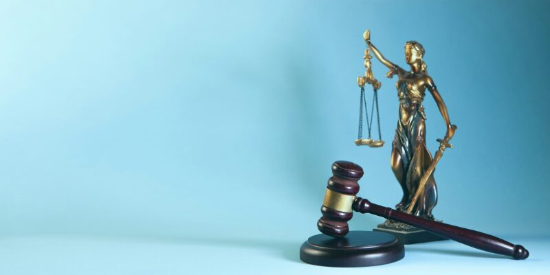 A figure of Lady justice and a judge's gavel symbolising legal representation in court.